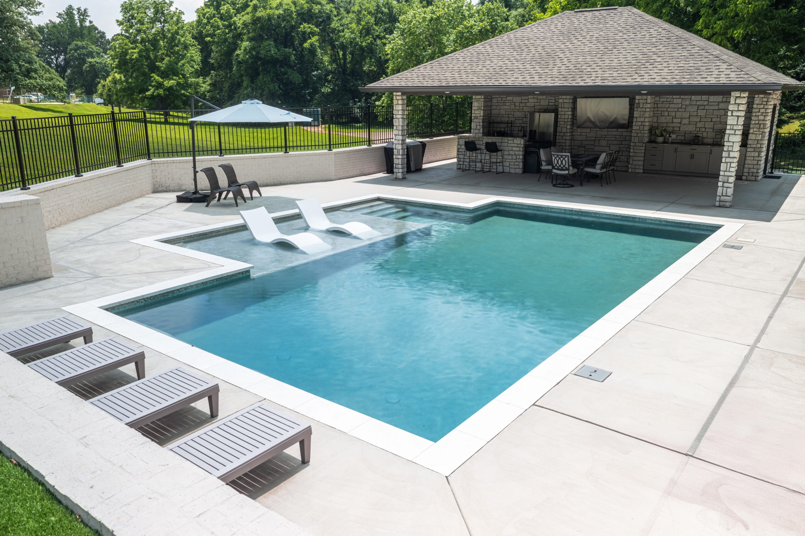 Finished custom concrete shotcrete pool with tile coping and surrounding deck